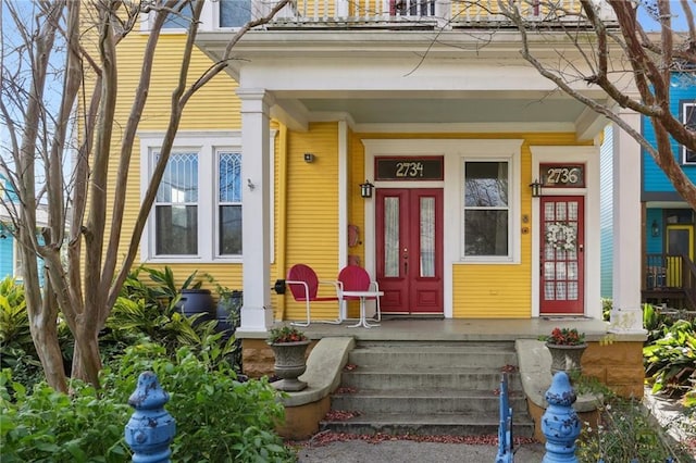 entrance to property with covered porch and a balcony