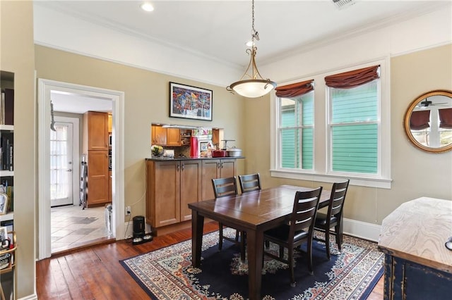 dining area with ornamental molding and dark wood-type flooring