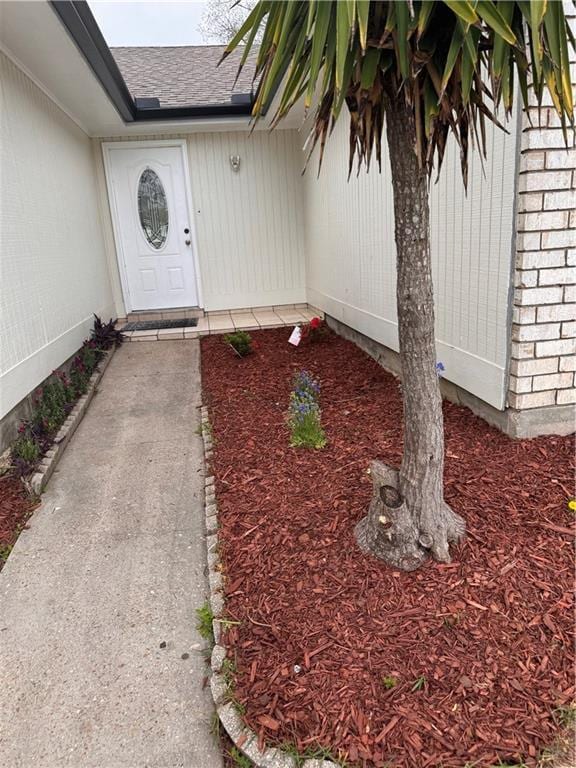 doorway to property featuring a shingled roof