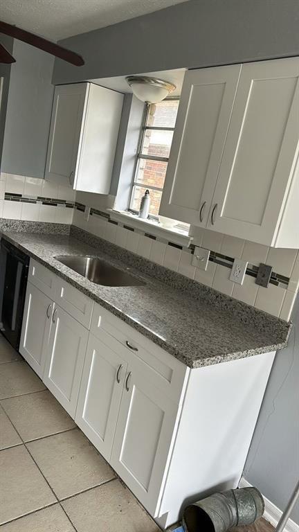 kitchen with tasteful backsplash, white cabinetry, sink, and light tile patterned flooring