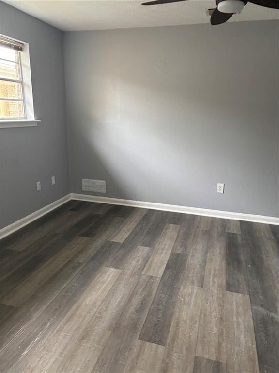 unfurnished room with visible vents, baseboards, dark wood-type flooring, and a ceiling fan