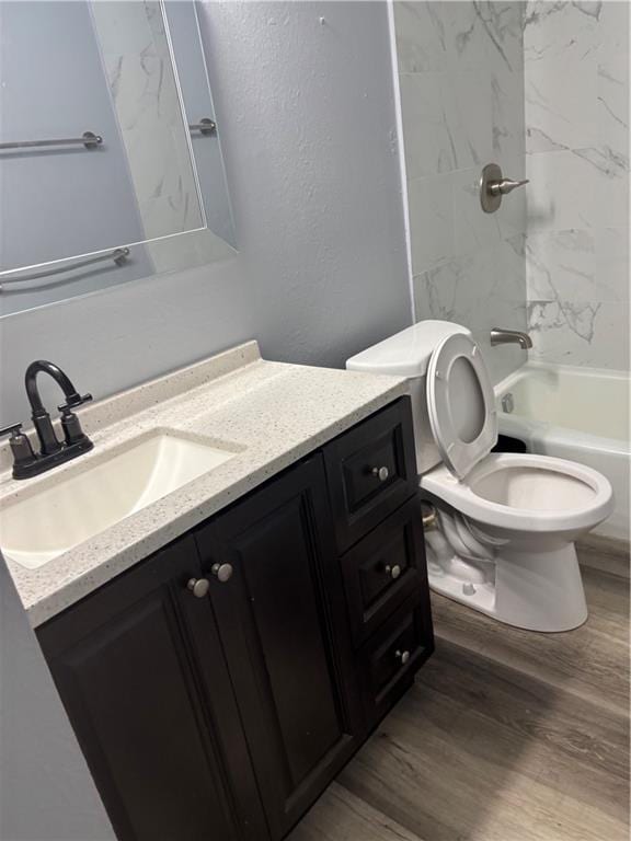 bathroom with toilet,  shower combination, wood finished floors, and vanity