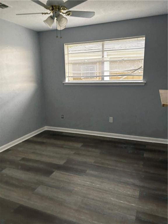 spare room featuring a wealth of natural light, visible vents, baseboards, and dark wood-style flooring