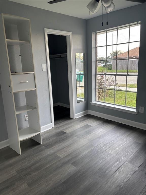 unfurnished bedroom with baseboards, multiple windows, and dark wood finished floors