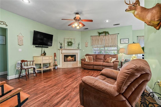 living room featuring a tiled fireplace, ceiling fan, and dark hardwood / wood-style flooring