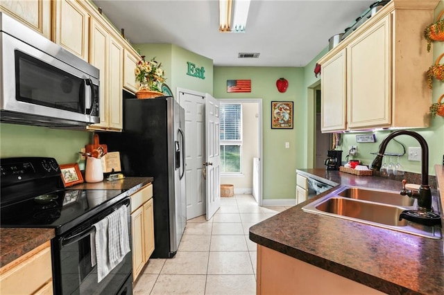 kitchen featuring cream cabinets, light tile patterned floors, sink, and black electric range