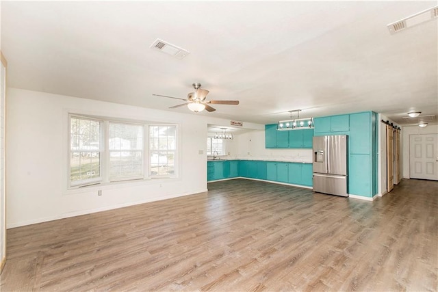 unfurnished living room featuring ceiling fan, light hardwood / wood-style floors, and sink