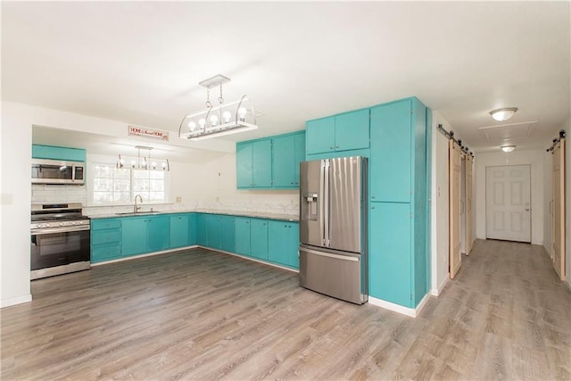 kitchen with appliances with stainless steel finishes, a barn door, blue cabinets, and sink