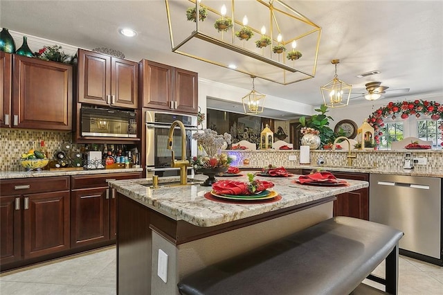 kitchen featuring decorative light fixtures, a kitchen bar, stainless steel appliances, and an island with sink