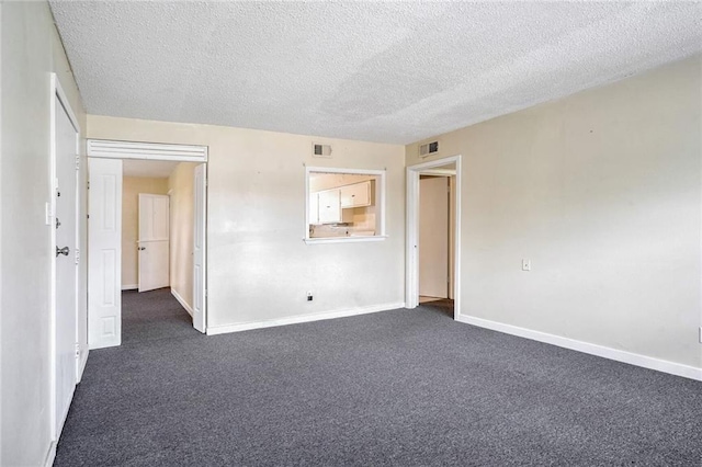 carpeted empty room with a textured ceiling