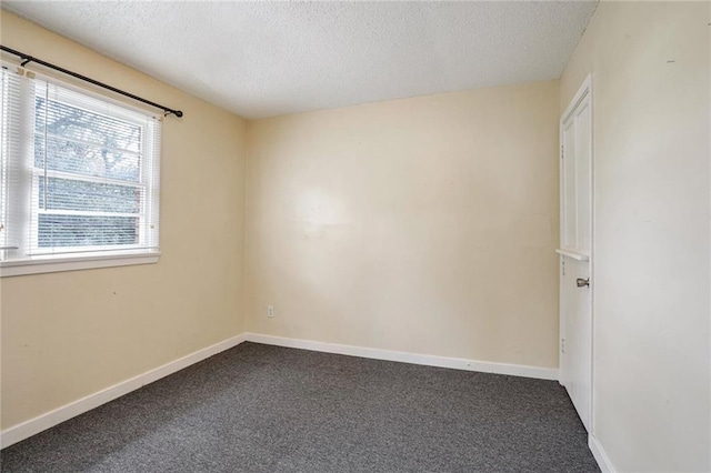 unfurnished room featuring dark colored carpet and a textured ceiling