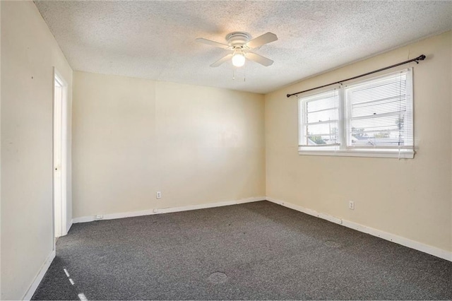 unfurnished room with ceiling fan, dark carpet, and a textured ceiling