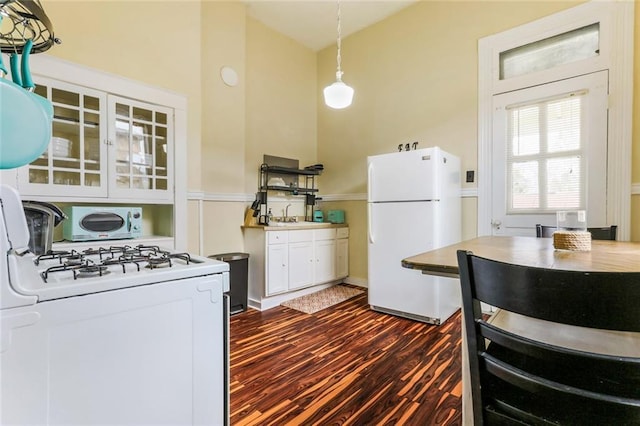 kitchen with white appliances, white cabinets, sink, decorative light fixtures, and dark hardwood / wood-style flooring