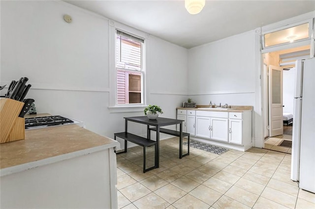 kitchen with sink, white cabinets, light tile patterned floors, and white refrigerator