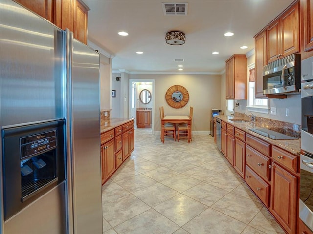 kitchen with light stone counters, ornamental molding, and appliances with stainless steel finishes