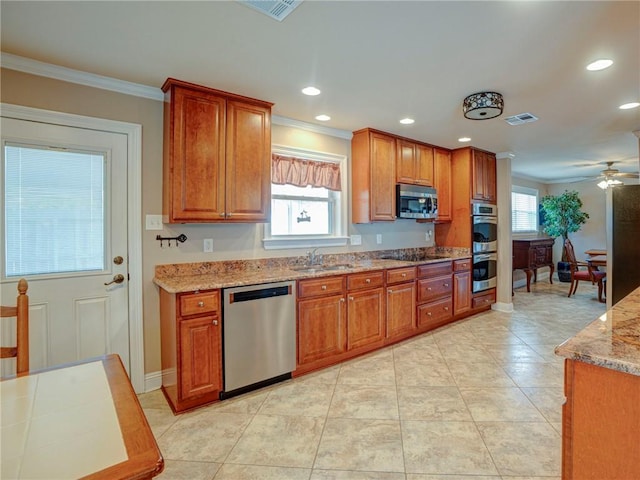 kitchen featuring light stone countertops, ceiling fan, sink, stainless steel appliances, and ornamental molding