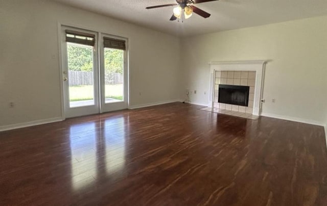 unfurnished living room featuring ceiling fan, dark hardwood / wood-style flooring, and a tiled fireplace