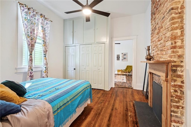 bedroom featuring a fireplace, ceiling fan, a closet, and dark wood-type flooring