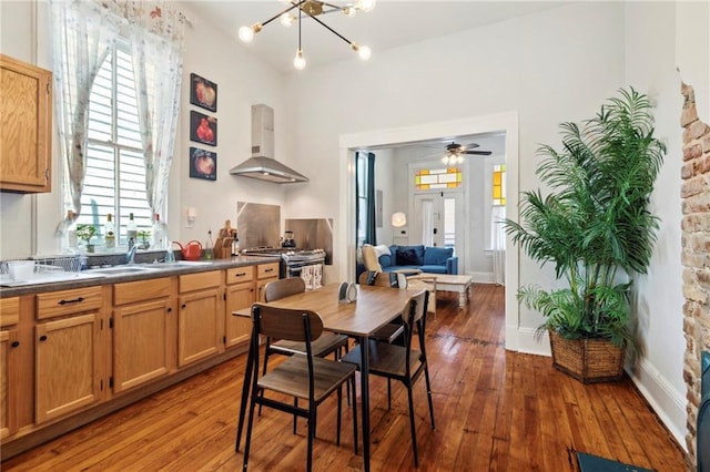 dining area featuring hardwood / wood-style floors, ceiling fan with notable chandelier, and sink