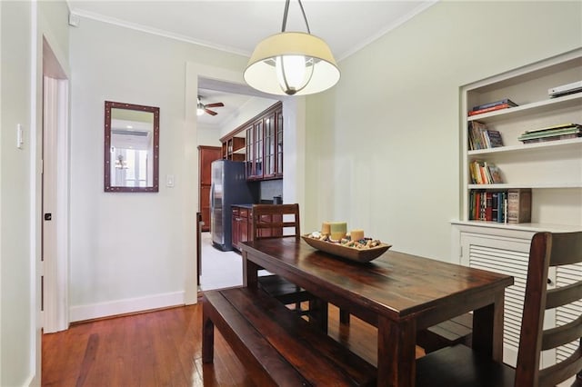 dining area with dark hardwood / wood-style floors, built in features, ornamental molding, and ceiling fan