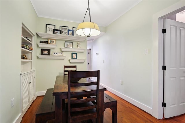 dining space featuring ornamental molding and dark wood-type flooring