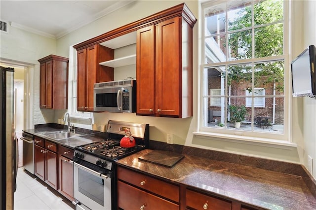 kitchen with stainless steel appliances, crown molding, sink, light tile patterned floors, and dark stone countertops