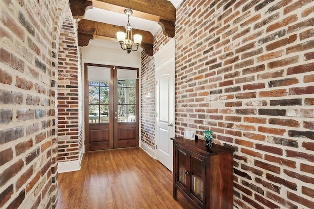 entryway featuring hardwood / wood-style flooring, beam ceiling, brick wall, and french doors