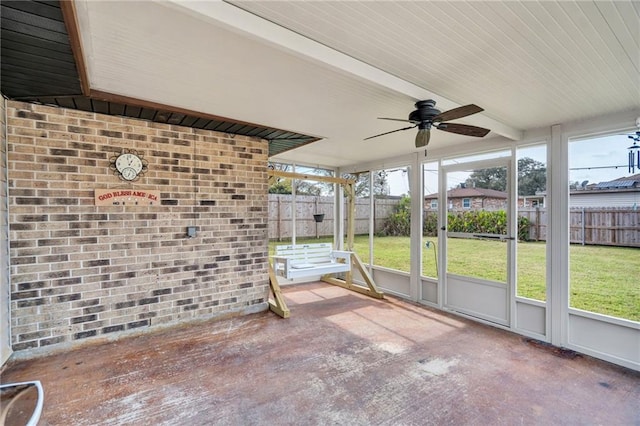 unfurnished sunroom with ceiling fan and beamed ceiling