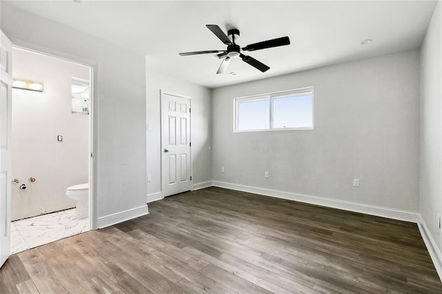 unfurnished bedroom featuring dark hardwood / wood-style floors, ensuite bath, and ceiling fan