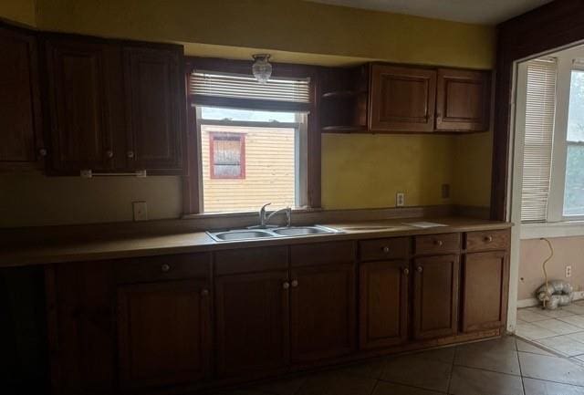 kitchen featuring light tile patterned floors, dark brown cabinetry, plenty of natural light, and sink