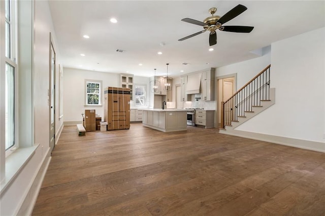 unfurnished living room featuring stairs, recessed lighting, wood finished floors, and a sink