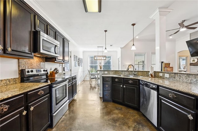 kitchen with light stone countertops, sink, stainless steel appliances, backsplash, and decorative light fixtures