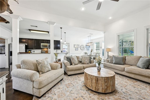 living room with decorative columns, ceiling fan, and crown molding