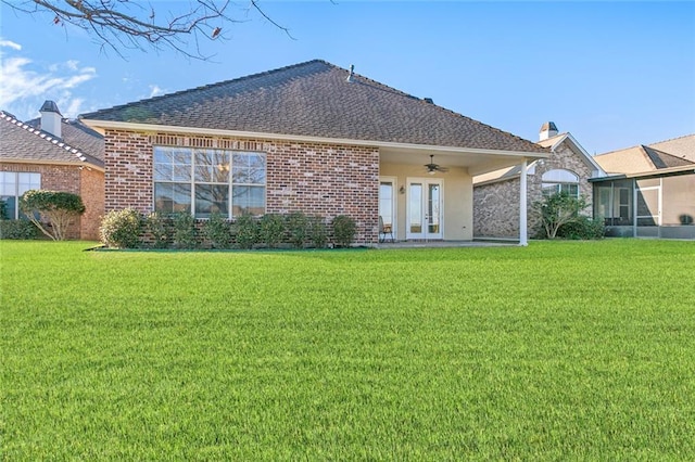 rear view of property with a lawn, ceiling fan, and french doors