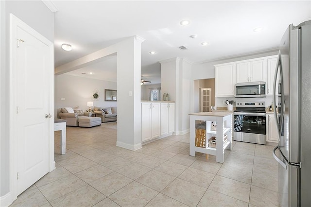 kitchen featuring stainless steel appliances, ceiling fan, crown molding, light tile patterned floors, and white cabinets