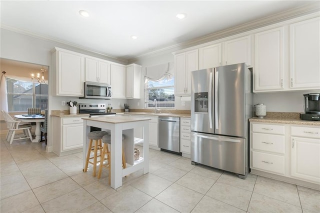 kitchen with white cabinetry, crown molding, a kitchen bar, light tile patterned floors, and appliances with stainless steel finishes