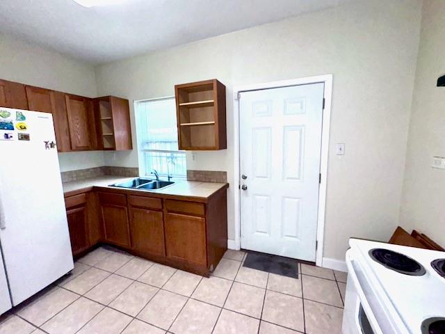 kitchen with sink, light tile patterned floors, and white appliances