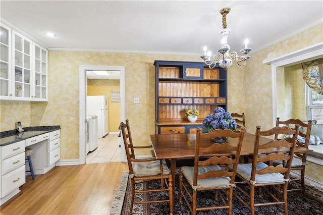 dining room with independent washer and dryer, a chandelier, light hardwood / wood-style floors, and ornamental molding