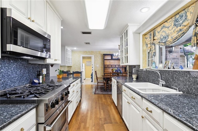 kitchen featuring white cabinetry, sink, tasteful backsplash, light hardwood / wood-style flooring, and appliances with stainless steel finishes