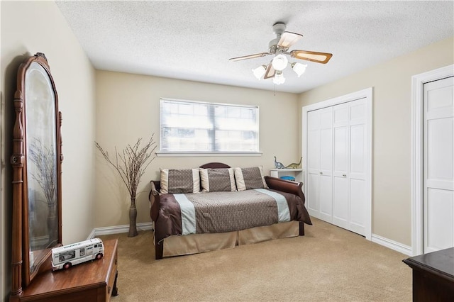 carpeted bedroom featuring ceiling fan and a textured ceiling