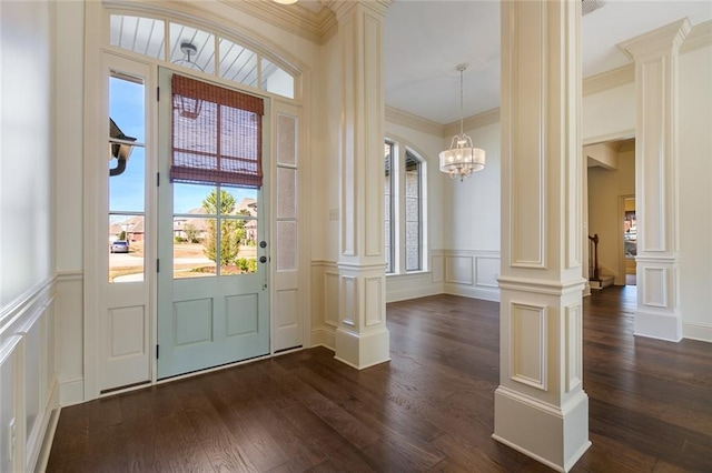 foyer with a notable chandelier, dark hardwood / wood-style floors, ornamental molding, and decorative columns