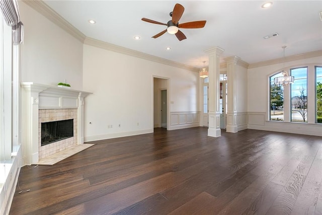 unfurnished living room featuring a tiled fireplace, dark hardwood / wood-style flooring, ceiling fan with notable chandelier, and ornamental molding