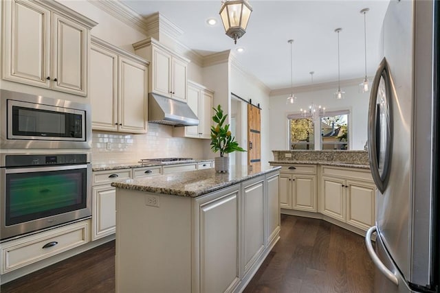 kitchen featuring a center island, hanging light fixtures, a barn door, cream cabinetry, and stainless steel appliances