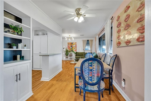 dining space featuring light hardwood / wood-style flooring and ceiling fan with notable chandelier