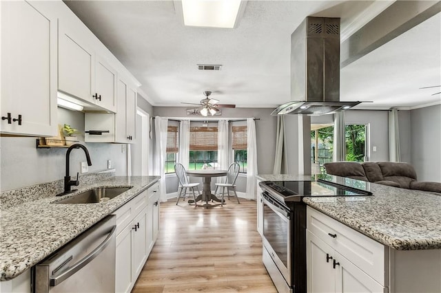 kitchen featuring sink, ceiling fan, island range hood, white cabinetry, and stainless steel appliances