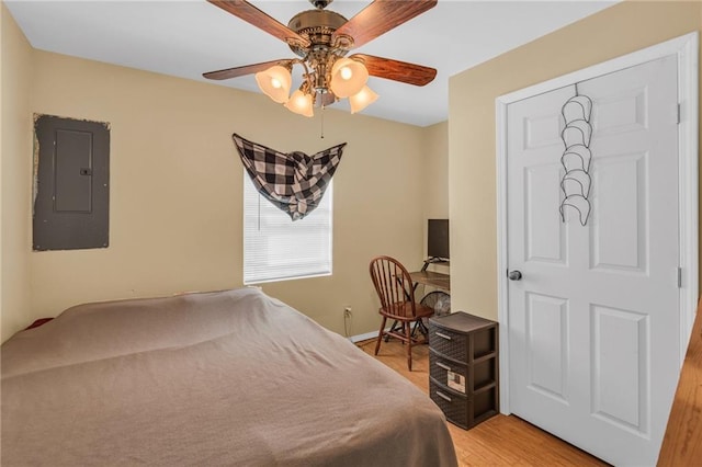 bedroom with wood-type flooring, electric panel, and ceiling fan