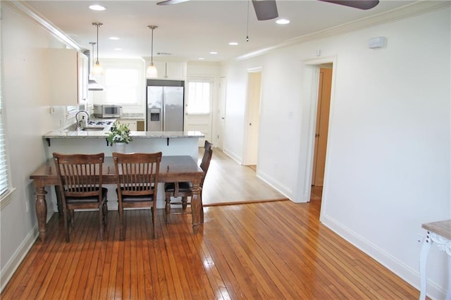 dining room featuring hardwood / wood-style flooring, ceiling fan, ornamental molding, and sink