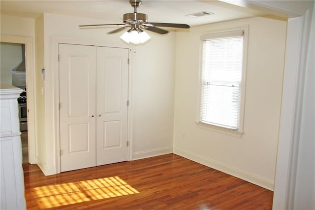 unfurnished bedroom with dark hardwood / wood-style flooring, a closet, and ceiling fan