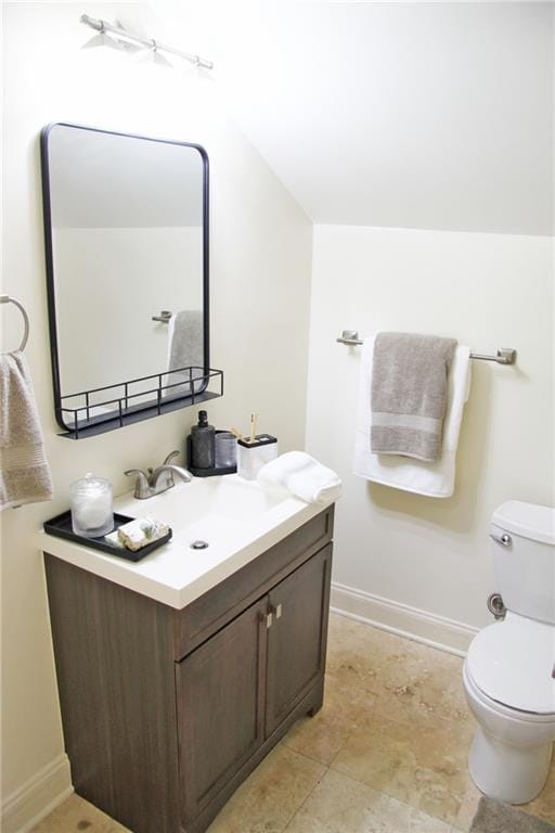 bathroom featuring vanity, toilet, and lofted ceiling