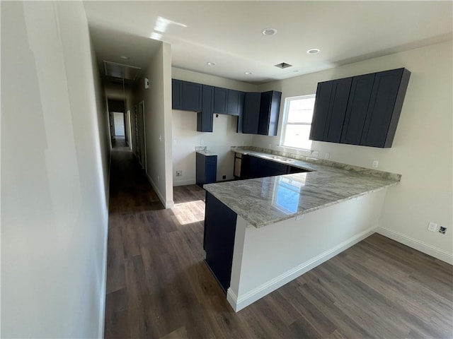 kitchen with kitchen peninsula, dark hardwood / wood-style floors, and light stone counters